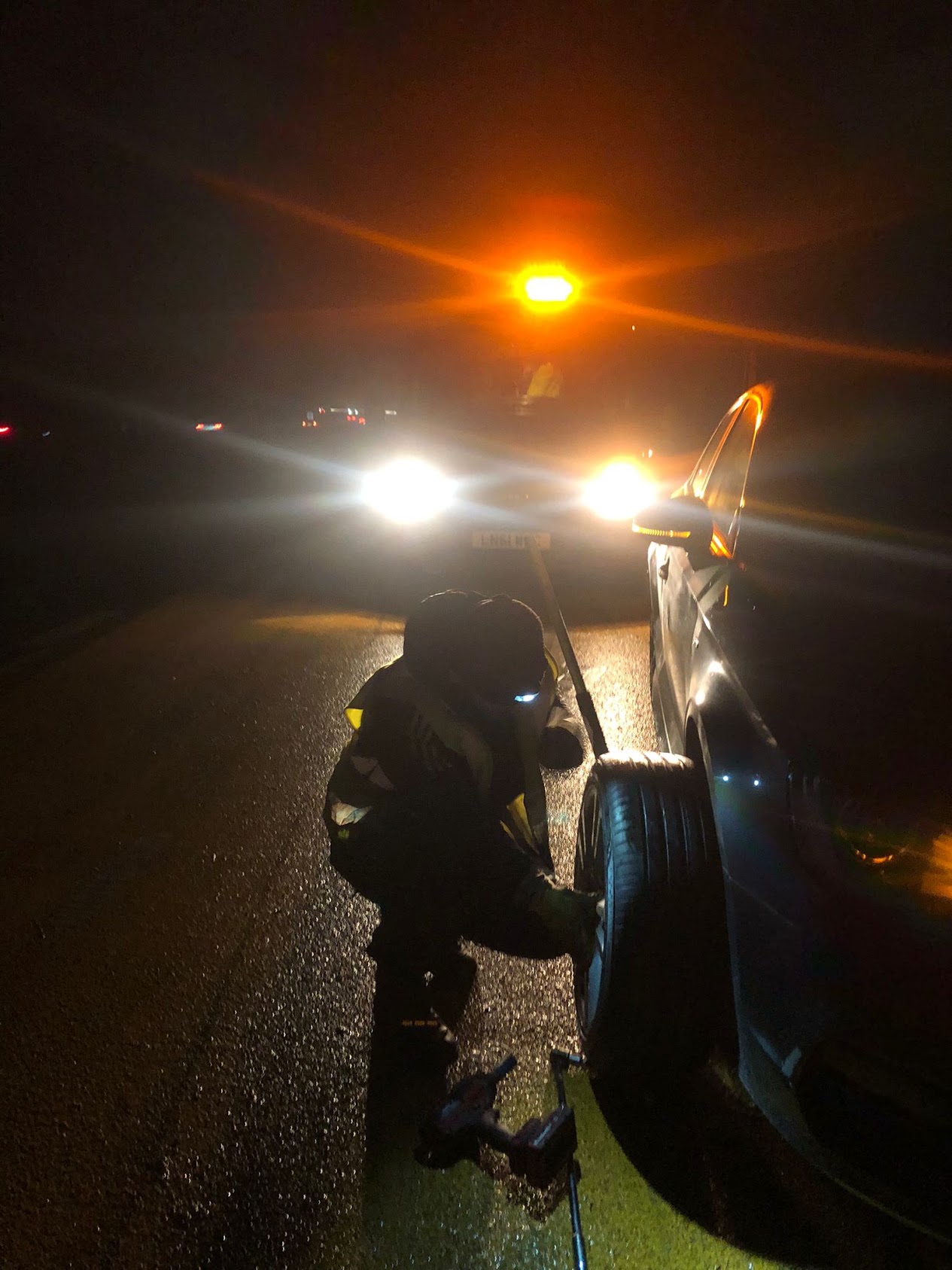 A BB Tyres technician changing a tyre at the roadside at night
